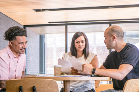 Two men and a woman sitting at a table looking at documents