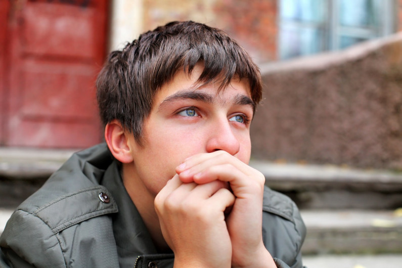 Close up of teenage boy thinking, chin on hands