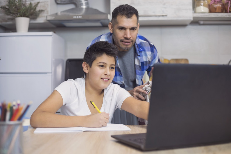 A father and son look at information on a laptop