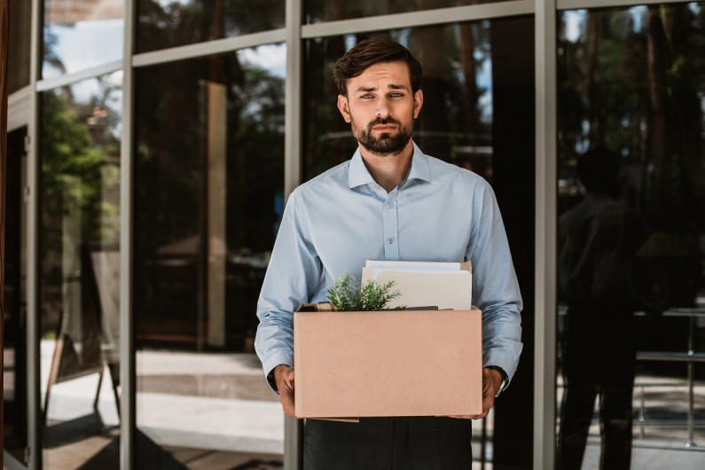 Man leaving office carrying plants and files in a box