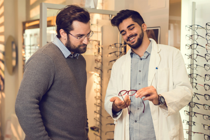 A male dispensing optician recommending a pair of glasses to a customer