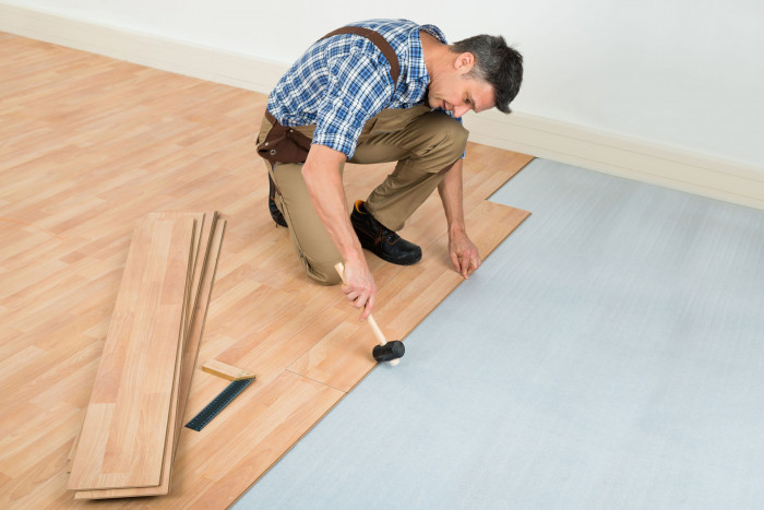 A flooring installer installing laminated hardwood 