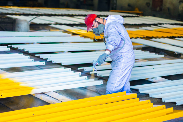 An industrial spray painter coating metal in a factory