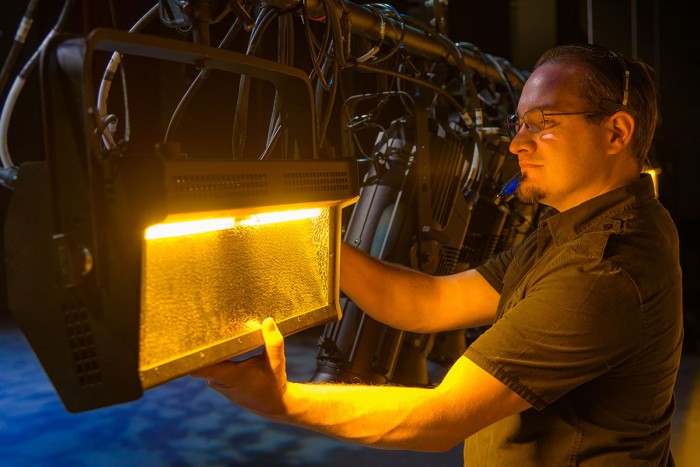 A lighting technician positions a light ahead of a show.